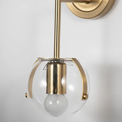 Modern wall light with gold frame cage and white glass bulb on neutral background stylish decorative lighting for bedroom decor.
