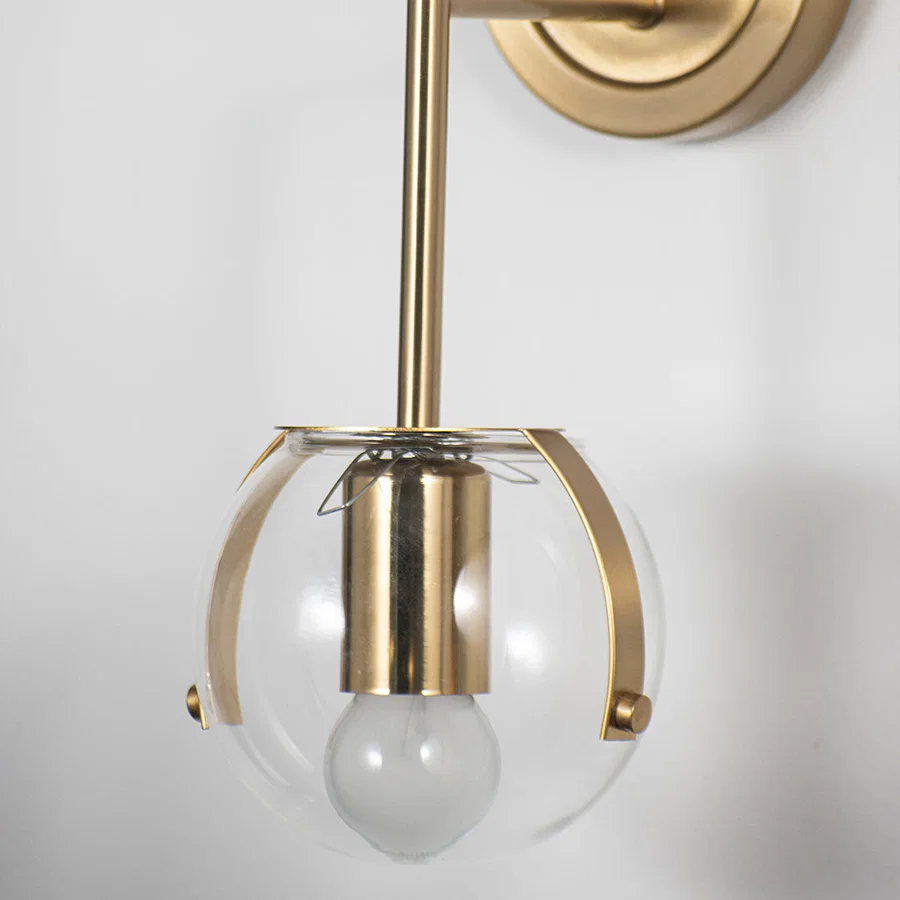 Modern wall light with gold frame cage and white glass bulb on neutral background stylish decorative lighting for bedroom decor.