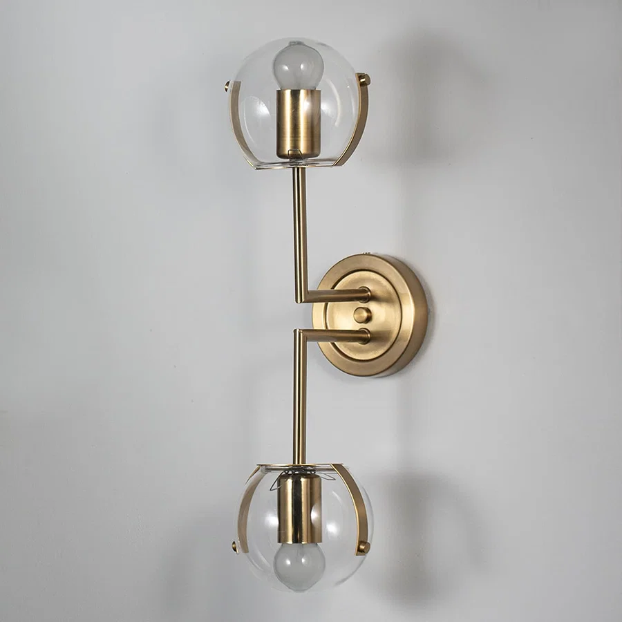 Wall sconce with double clear glass globes and gold finish frame perfect for bedroom living room and luxury modern interiors.
