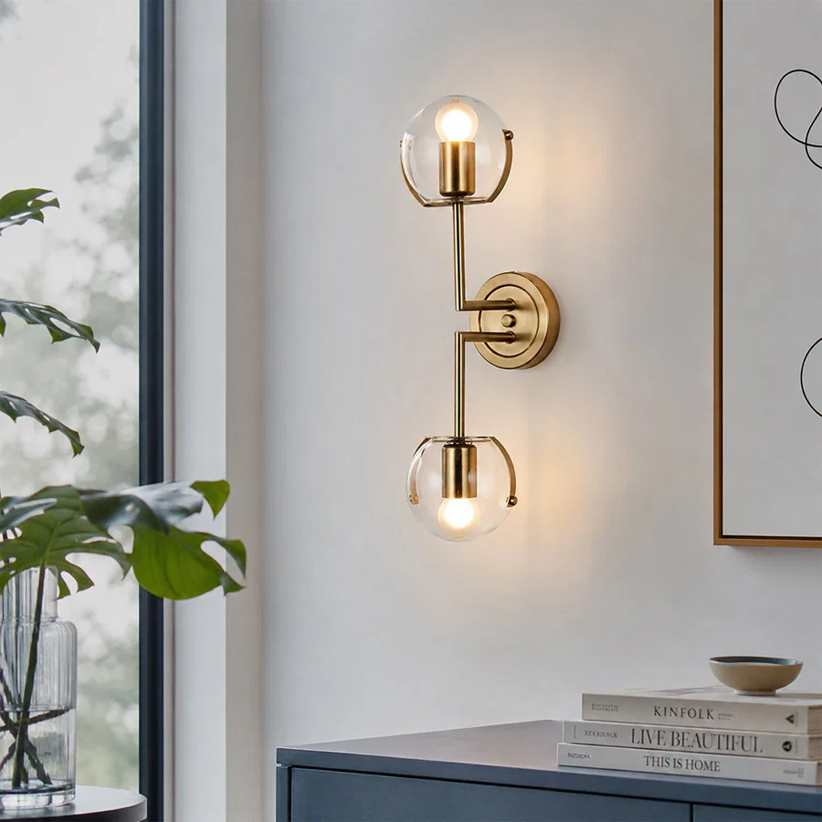 Modern gold metal wall light with frosted glass globes for bedroom hallway and luxury home interiors with warm lighting.