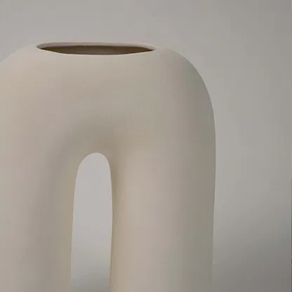 Closeup of white ceramic decorative vase with arch cutout design highlighting refined modern craftsmanship details.