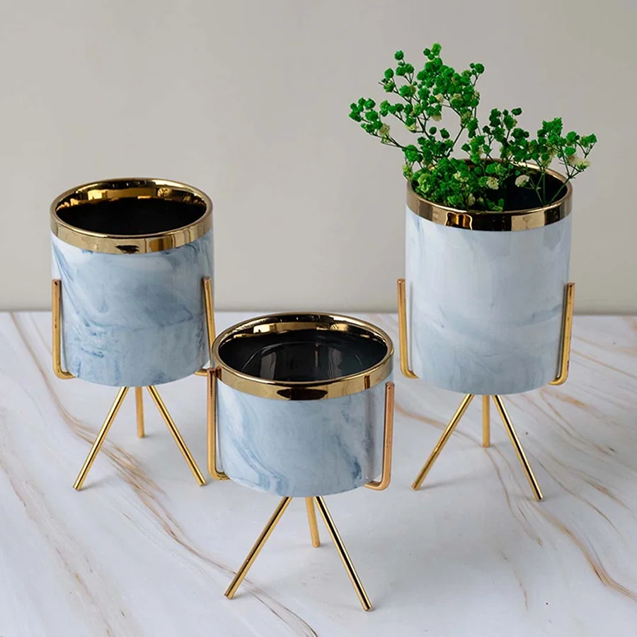 A stylish marble finish planter with gold metal stand styled on a clean lifestyle backdrop creating a modern accent for home decor.