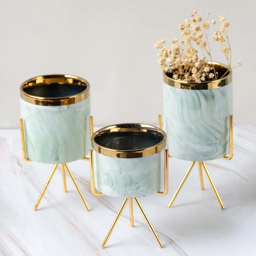 Small marble-textured planter with gold stand styled on a clean marble surface  adding a chic modern accent to the lifestyle setting.