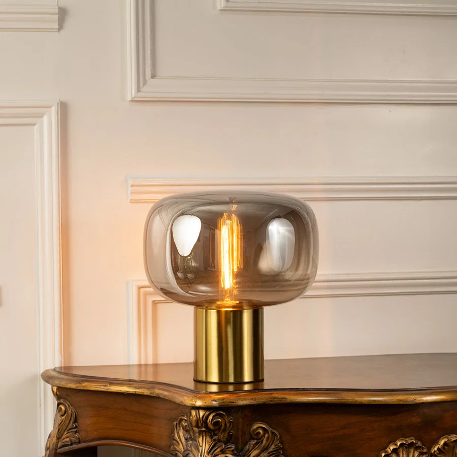 Smoked glass table lamp shade with brass metal base showcasing modern craftsmanship and decorative lighting appeal.
