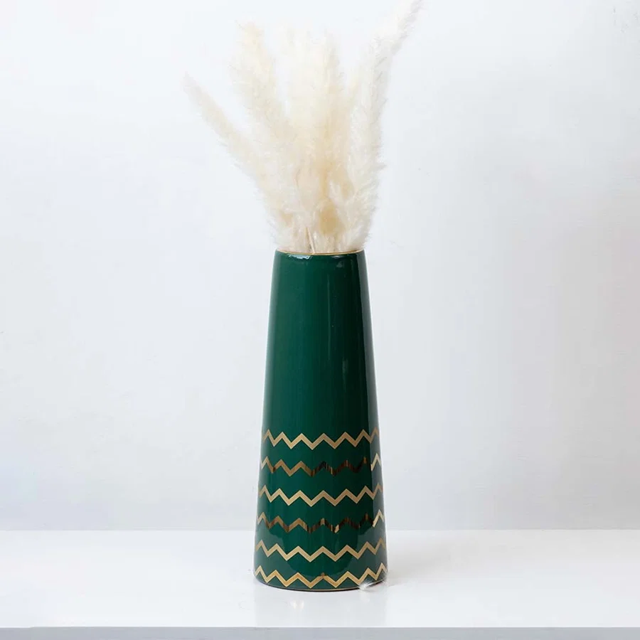 Elegant green ceramic vase with golden zigzag design styled with pampas grass for modern home decor.