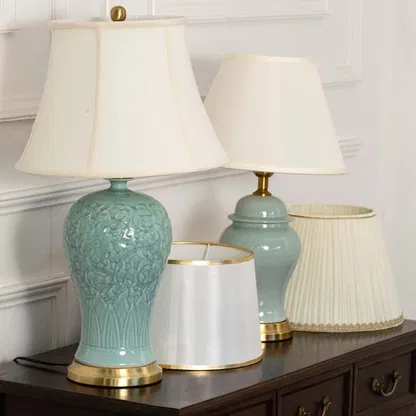 Elegant two blue ceramic table lamps with gold metal base and white fabric shade adds a soft refined touch to home decor.