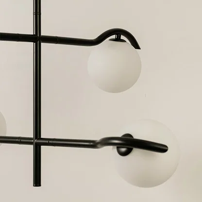 Closeup view of black metal chandelier showing curved metal arms and matte white globes for stylish modern interior lighting.
