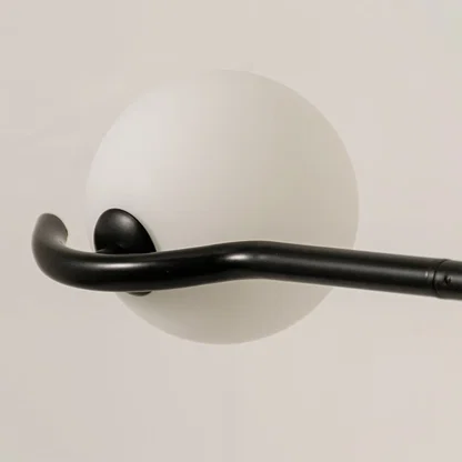 Detailed closeup of black chandelier highlighting sculpted arms and smooth white globes for contemporary home lighting decor.