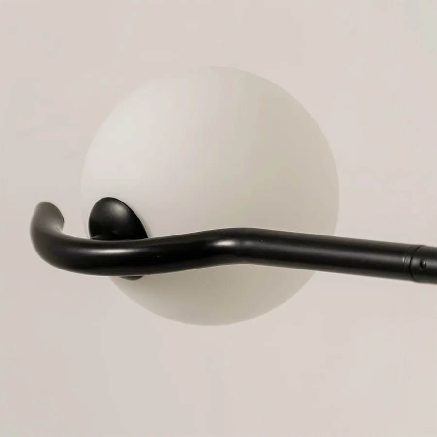 Detailed closeup of black chandelier highlighting sculpted arms and smooth white globes for contemporary home lighting decor.
