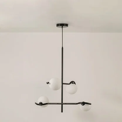 Black metal chandelier with white globes shown on a bright white background with lights off for a sleek minimal modern look.
