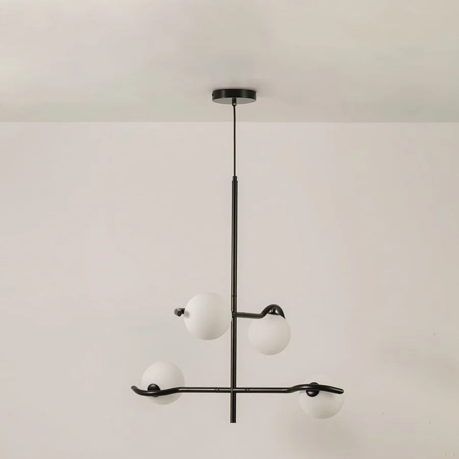 Black metal chandelier with white globes shown on a bright white background with lights off for a sleek minimal modern look.