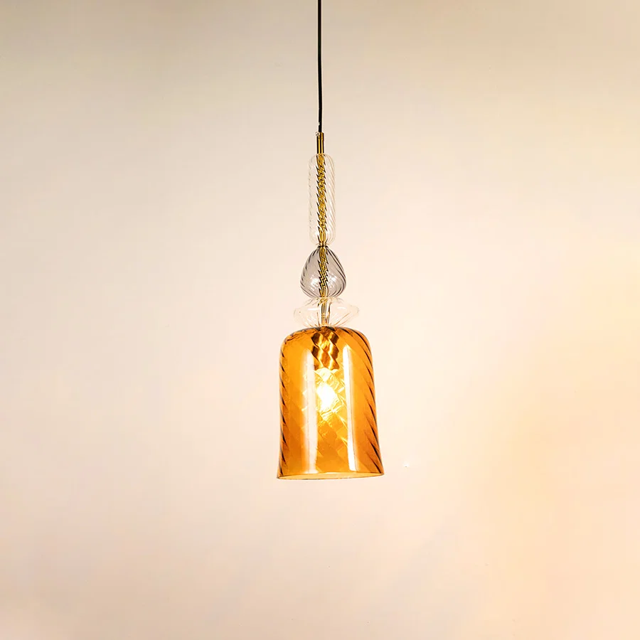 Amber glass pendant light illuminated to display elegant hanging light design with warm decorative lighting effects.