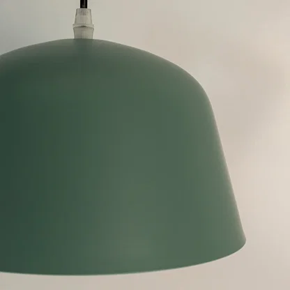Closeup of green metal pendant light showcasing smooth surface and refined modern craftsmanship.