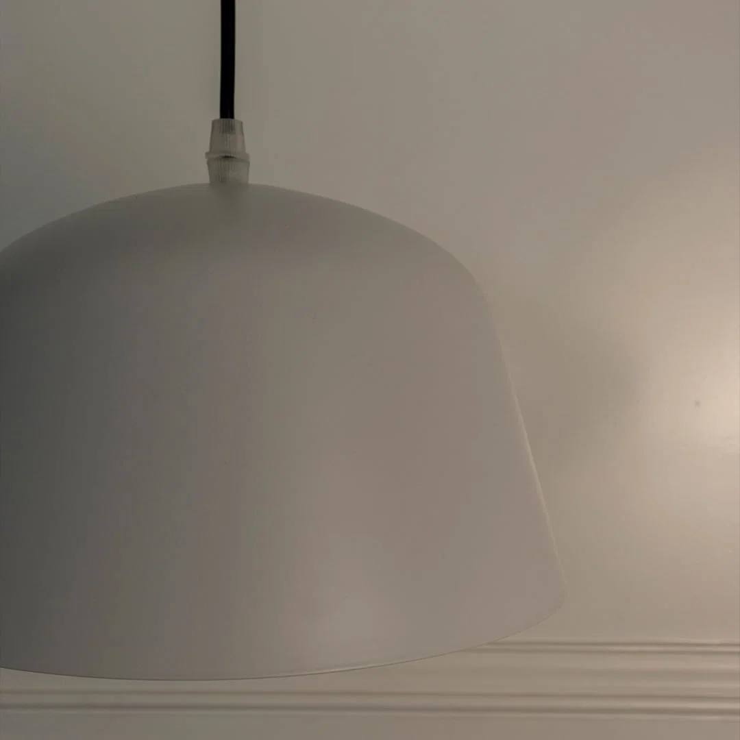 Closeup of white metal pendant light showcasing smooth finish and refined modern craftsmanship.