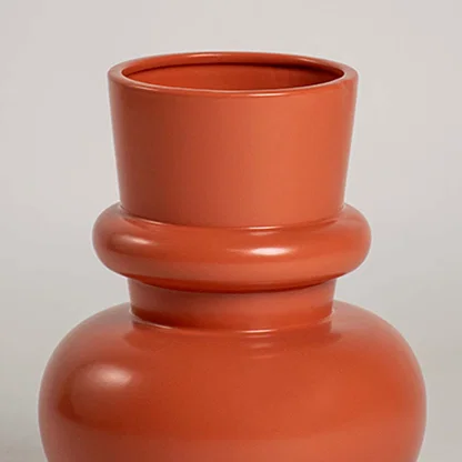 Closeup of terracotta orange modern decorative vase showing smooth rounded shape and refined finish ideal for enhancing contemporary interiors.