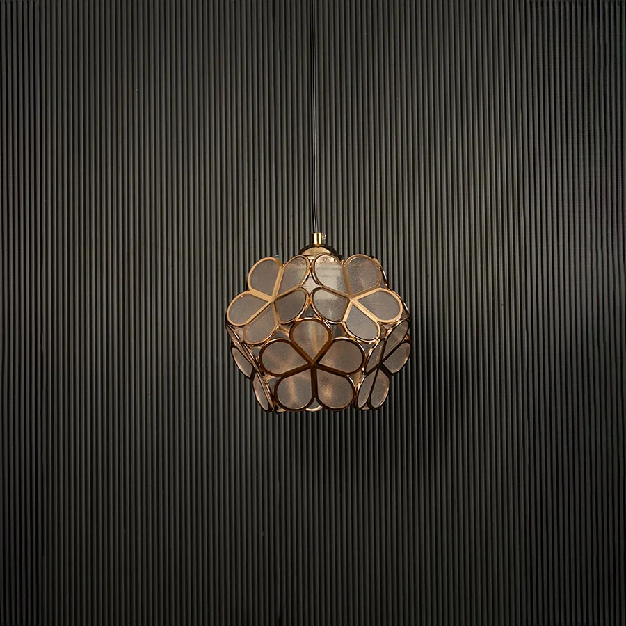 Modern gold flower pendant light displayed on dark background with light off highlighting elegant design details.