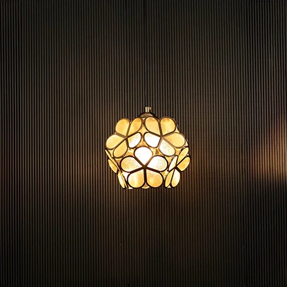 Elegant gold floral pendant light illuminated on dark background showcasing its artistic handcrafted metal design.
