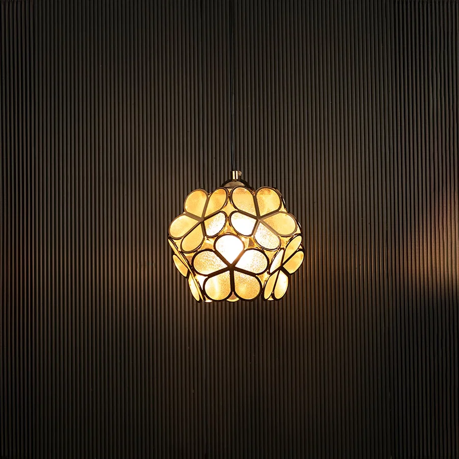Elegant gold floral pendant light illuminated on dark background showcasing its artistic handcrafted metal design.