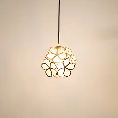 Gold floral metal pendant light glowing on white background creating stylish decorative lighting for modern homes.