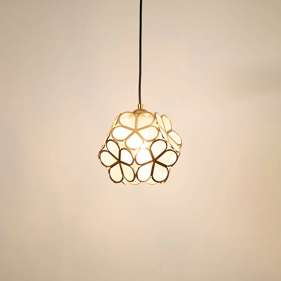 Gold floral metal pendant light glowing on white background creating stylish decorative lighting for modern homes.