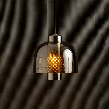 Smoke grey glass pendant light with dome shade casting warm ambient glow imagined against a dark background creating a dramatic modern interior decor atmosphere.