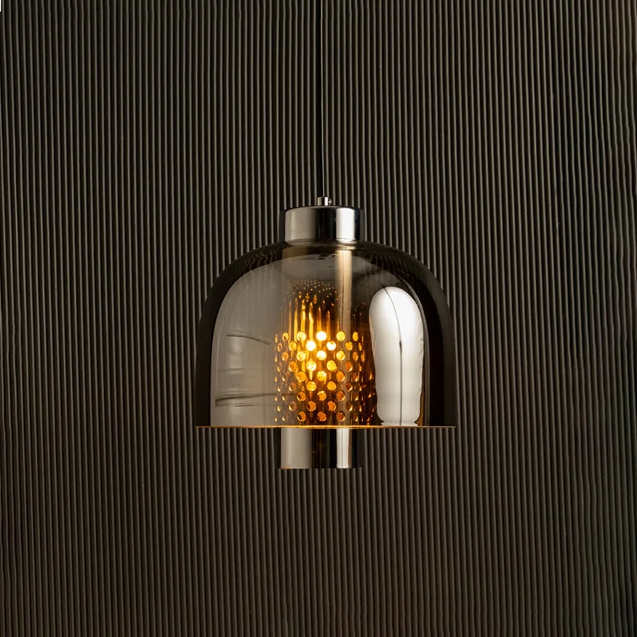 Smoke grey glass pendant light with dome shade casting warm ambient glow imagined against a dark background creating a dramatic modern interior decor atmosphere.