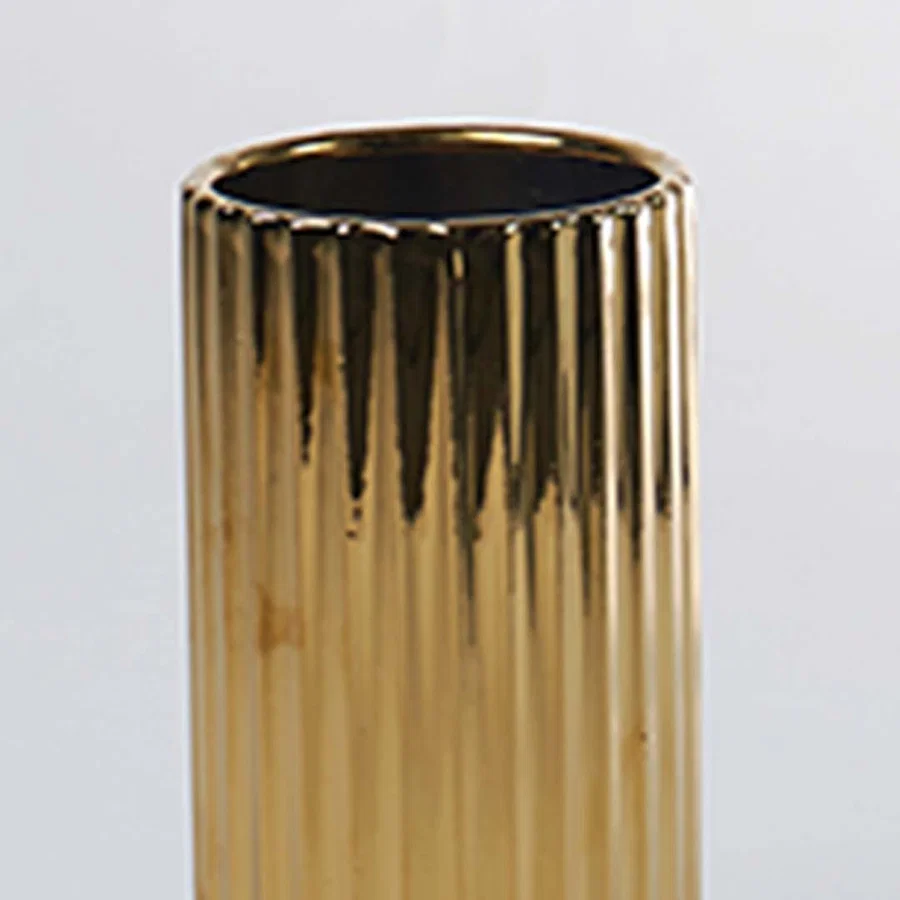 A closeup of a gold ribbed vase capturing its glossy reflective texture and detailed finish creating a refined modern look with elegant highlights.