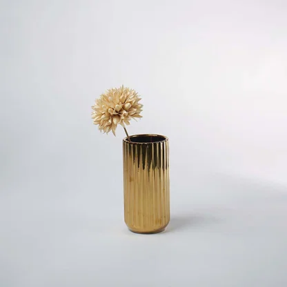 A reflective gold ribbed vase placed in a minimal scene offering a second lifestyle view that highlights its tall shape and modern metallic charm.