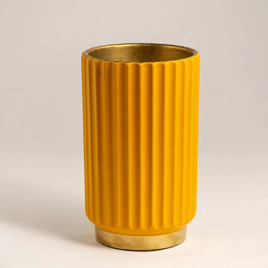 Mustard yellow ceramic decorative vase with fluted texture and gold rim for contemporary shelf styling and decor.