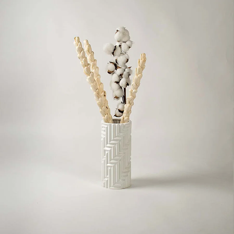 A stylish white textured vase showcased in a minimal lifestyle setup with soft shadows enhancing its sculpted modern design.