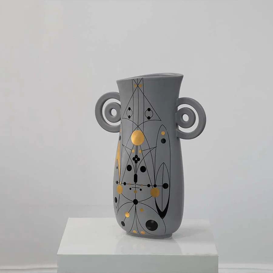 Grey ceramic vase with abstract gold and black detailing and loop handles displayed on a clean white background for modern decor styling.
