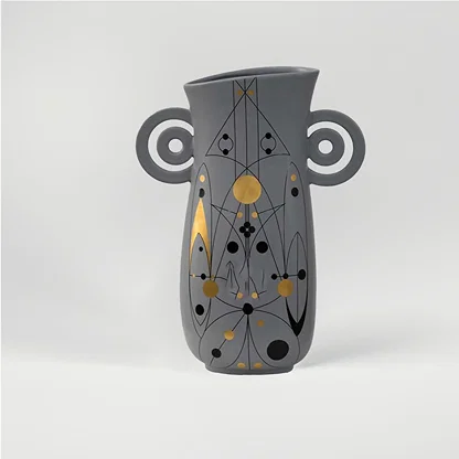 Grey ceramic decorative vase with artistic handles and gold dot detailing for modern shelf decor and styling.