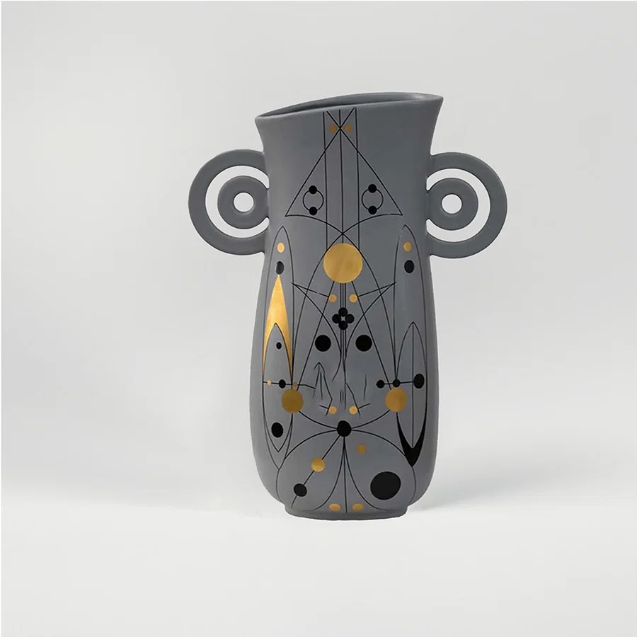 Grey ceramic decorative vase with artistic handles and gold dot detailing for modern shelf decor and styling.