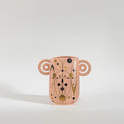 Peach ceramic decorative vase with artistic handle design and gold accents for contemporary home decor styling.