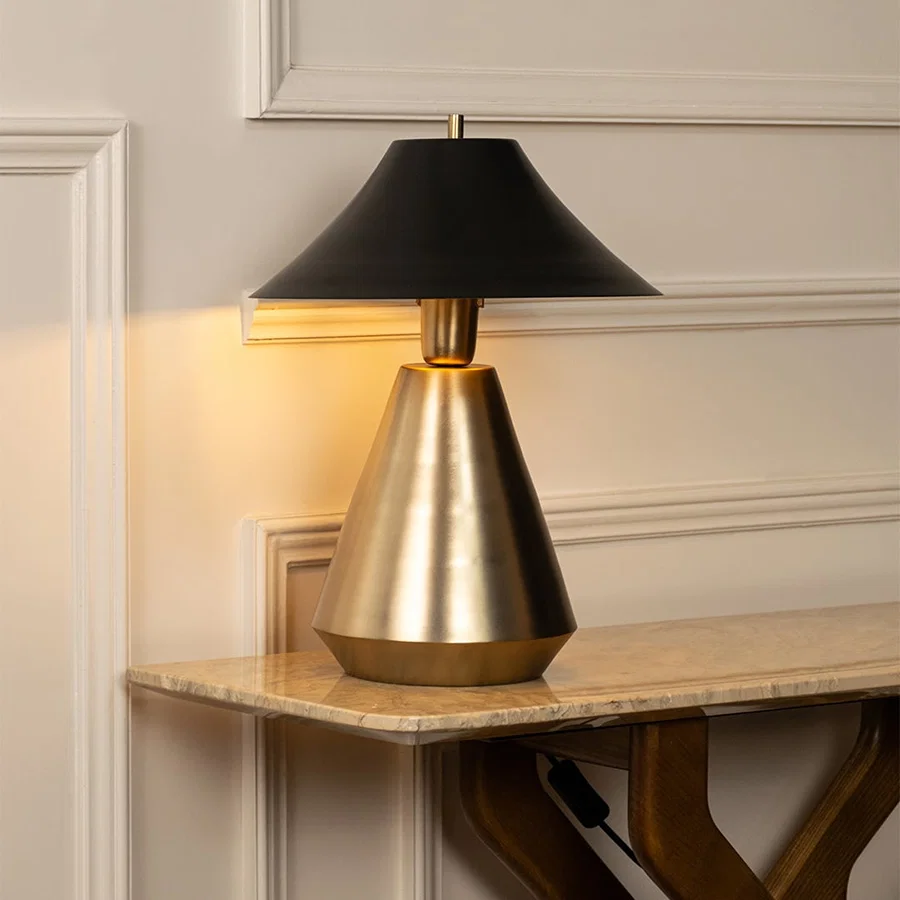 Designer metal table lamp with a black shade and sleek gold base blending minimalist design and luxury aesthetics for stylish interior lighting.