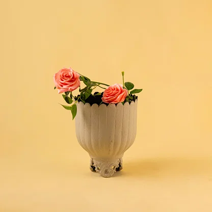 Ribbed light grey metal planter with pink flowers for modern home decor and stylish tabletop accent display.