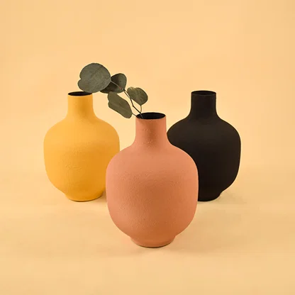 Trio of colorful matte round metal vases for vibrant modern home decor and artistic tabletop centerpiece arrangement.