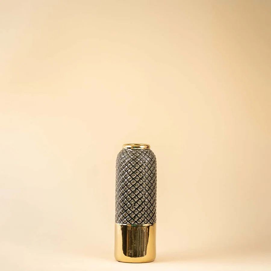 Tall textured ceramic vase in grey with a glossy golden base standing on a plain white background showcasing its elegant pattern and reflective metallic finish.