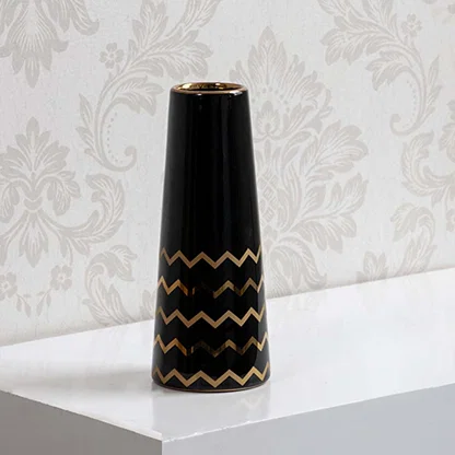 A sleek black ceramic vase with gold zigzag detailing shown on a bright background highlighting its glossy finish and modern artistic style.