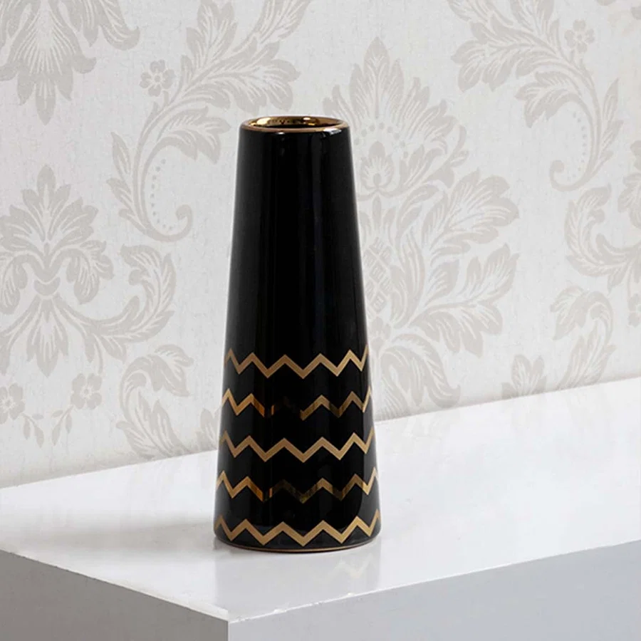 A sleek black ceramic vase with gold zigzag detailing shown on a bright background highlighting its glossy finish and modern artistic style.