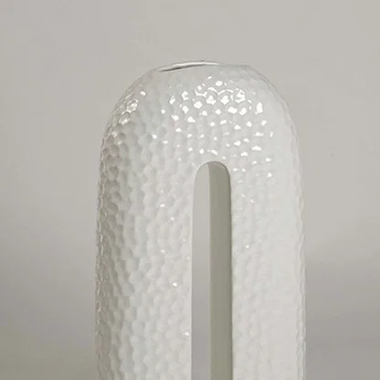 Closeup showing detailed texture and glossy surface of handcrafted white ceramic U-shaped decorative vase.