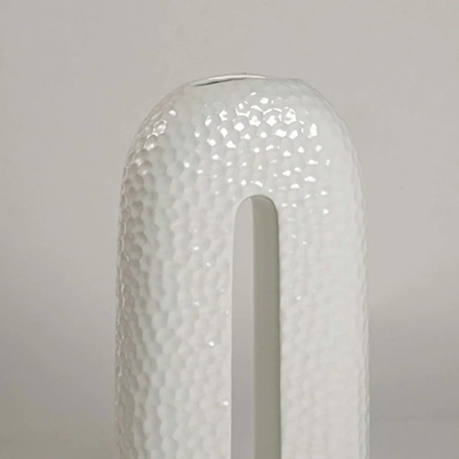 Closeup showing detailed texture and glossy surface of handcrafted white ceramic U-shaped decorative vase.