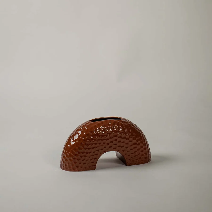 Modern low crescent arch shaped ceramic vase with a brown dotted texture on white background for contemporary styling.