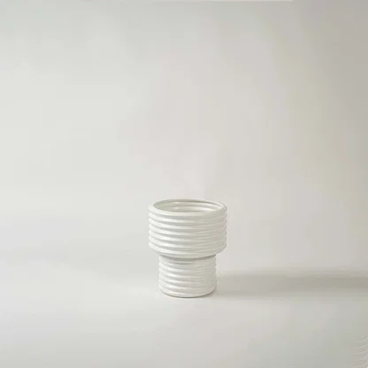 White ribbed ceramic decorative vase with layered design for shelf styling and minimalist home decor display.