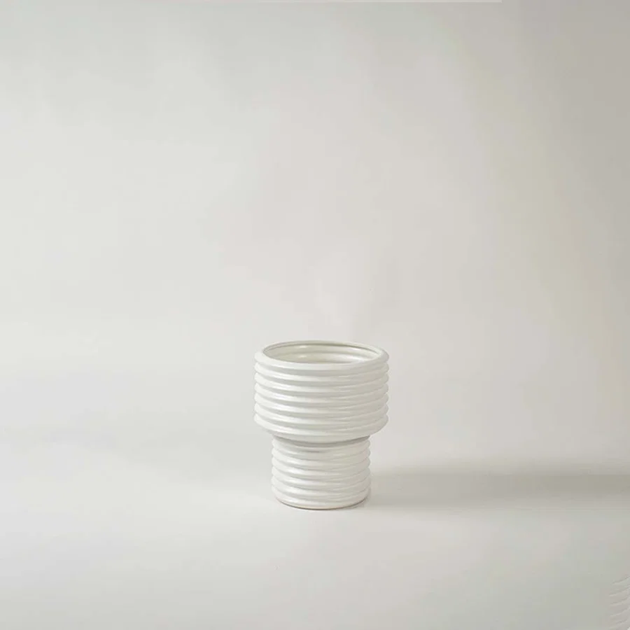 White ribbed ceramic decorative vase with layered design for shelf styling and minimalist home decor display.