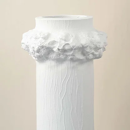 Detailed closeup of white ceramic vase showing textured finish and floral crown detail for decorative styling.