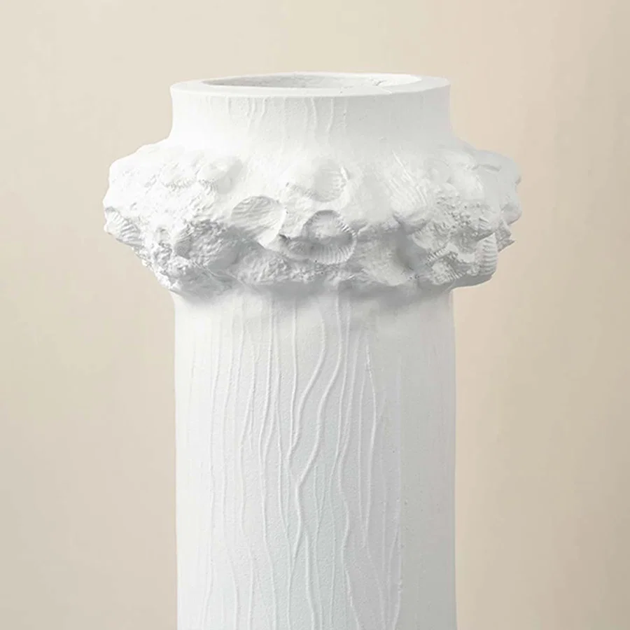 Detailed closeup of white ceramic vase showing textured finish and floral crown detail for decorative styling.