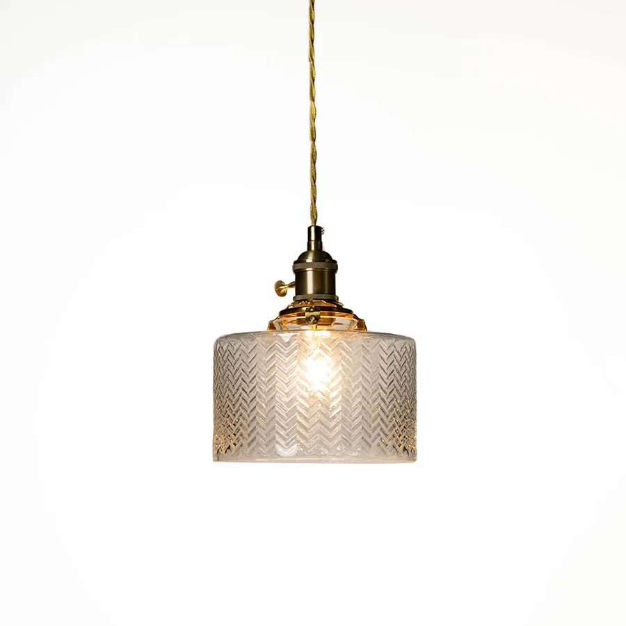 Textured clear glass and brass metal pendant light designed for elegant dining room decor spaces.