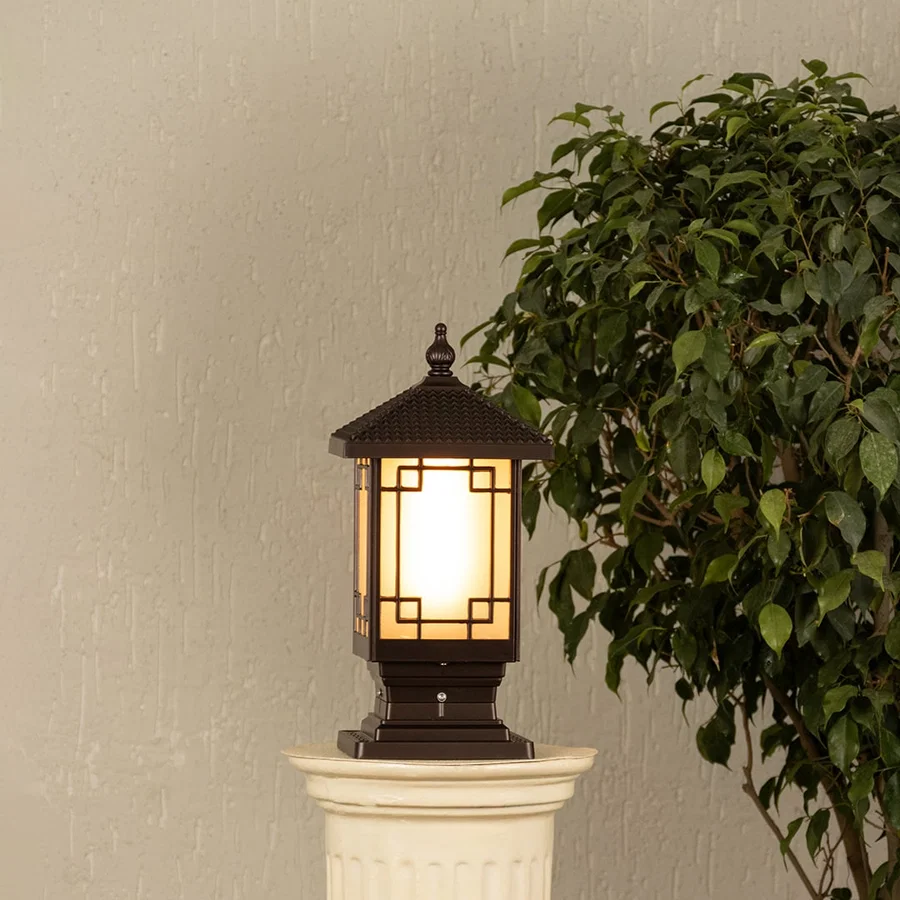 Black metal outdoor post lantern Light On mounted on a stone pillar Traditional garden gate lighting Main Lifestyle image at night.