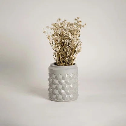 Modern grey ceramic vase with geometric texture displayed in a lifestyle setting enhancing the decor with a subtle contemporary touch.